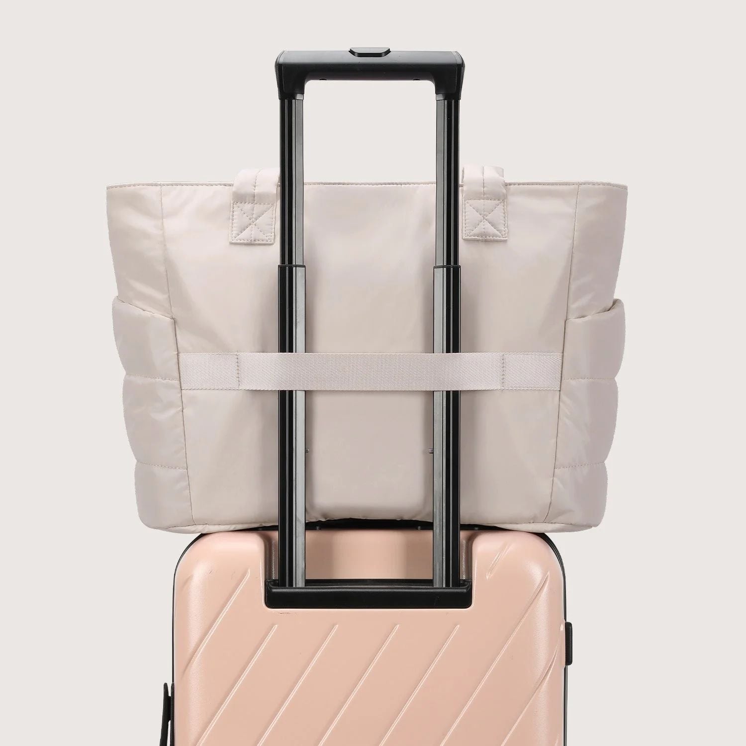 Beige tote bag strapped onto a suitcase trolley handle
