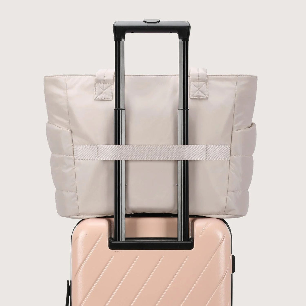 Beige tote bag strapped onto a suitcase trolley handle