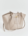 Beige leather tote bag with twist-lock strap detail, angled front view