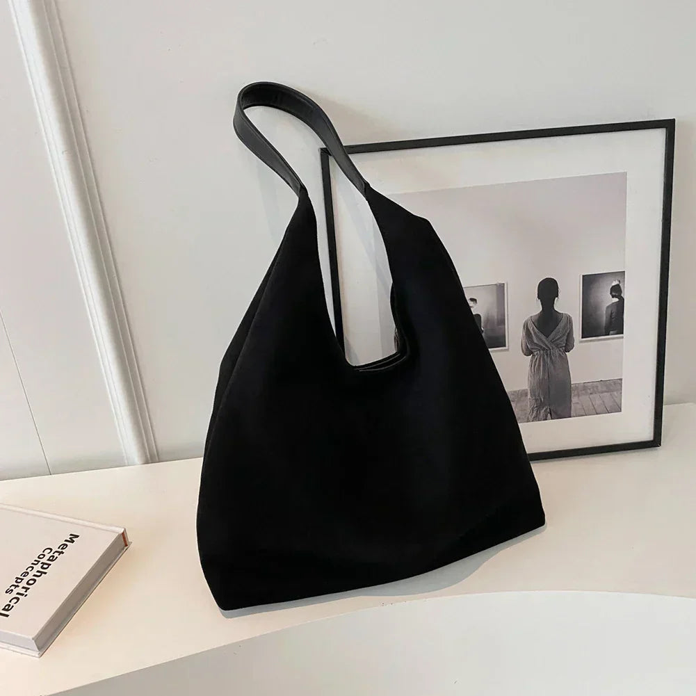 Black suede shoulder tote bag on a desk