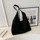Black suede shoulder tote bag on a desk