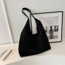 Black suede shoulder tote bag on a desk