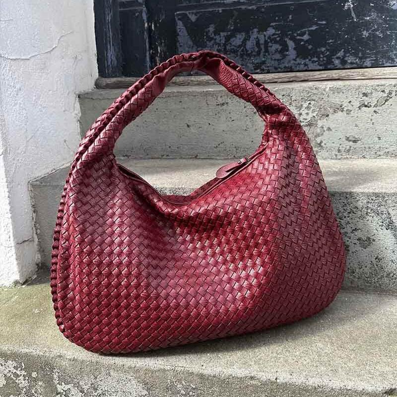 Burgundy woven leather hobo bag resting on stone steps outdoors