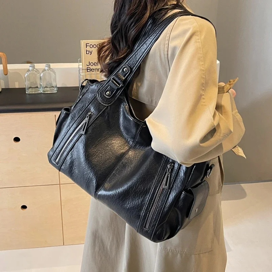 Midnight black leather shoulder bag worn on shoulder, side view