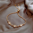 Gold bracelet with opal fish charms, close-up flat lay on dark satin
