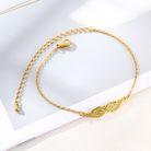 Gold angel wing bracelet, styled flat lay on textured surface