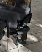 Close-up of charcoal cape scarf detail, model seated outdoors