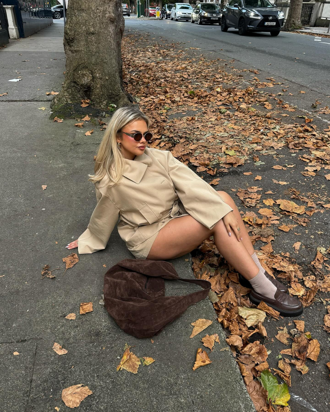 Beige trench jacket and shorts set, model sitting on pavement