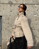 Sand short trench coat with high collar and belt, side view on model