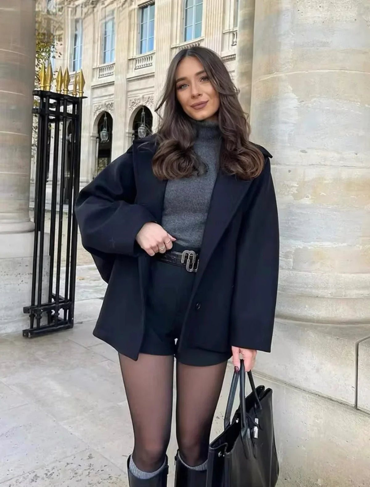 Black oversized coat over grey jumper and shorts, front view