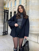 Black oversized coat over grey jumper and shorts, front view