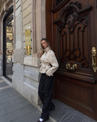 Sand short trench coat, model leaning against doorway, side view