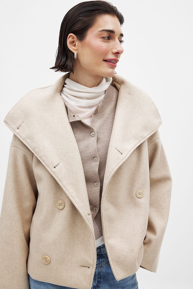 Close-up of light beige double-breasted coat on model