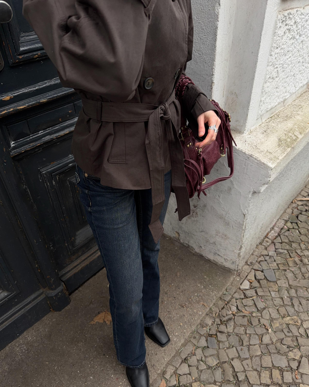 Close-up of brown trench coat belt and hem on model