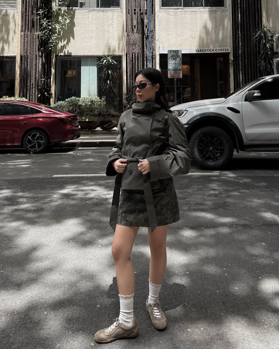 Olive green short belted trench coat, full-length front view on street