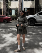 Olive green short belted trench coat, full-length front view on street