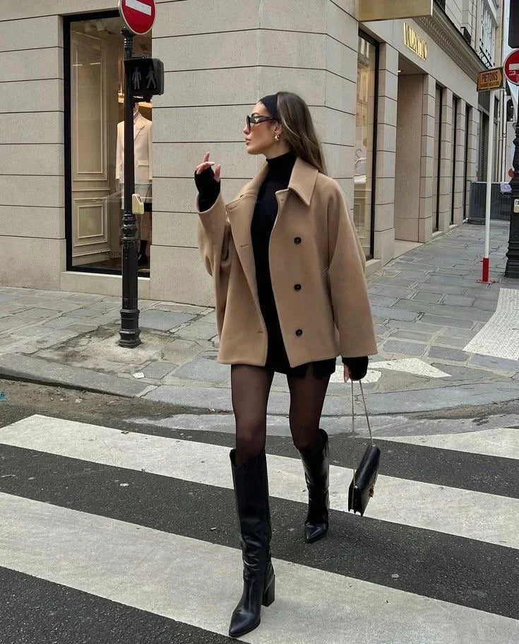 Beige oversized coat over black dress, front view walking