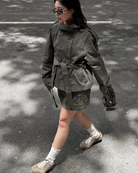 Olive green short belted trench coat, model walking outdoors