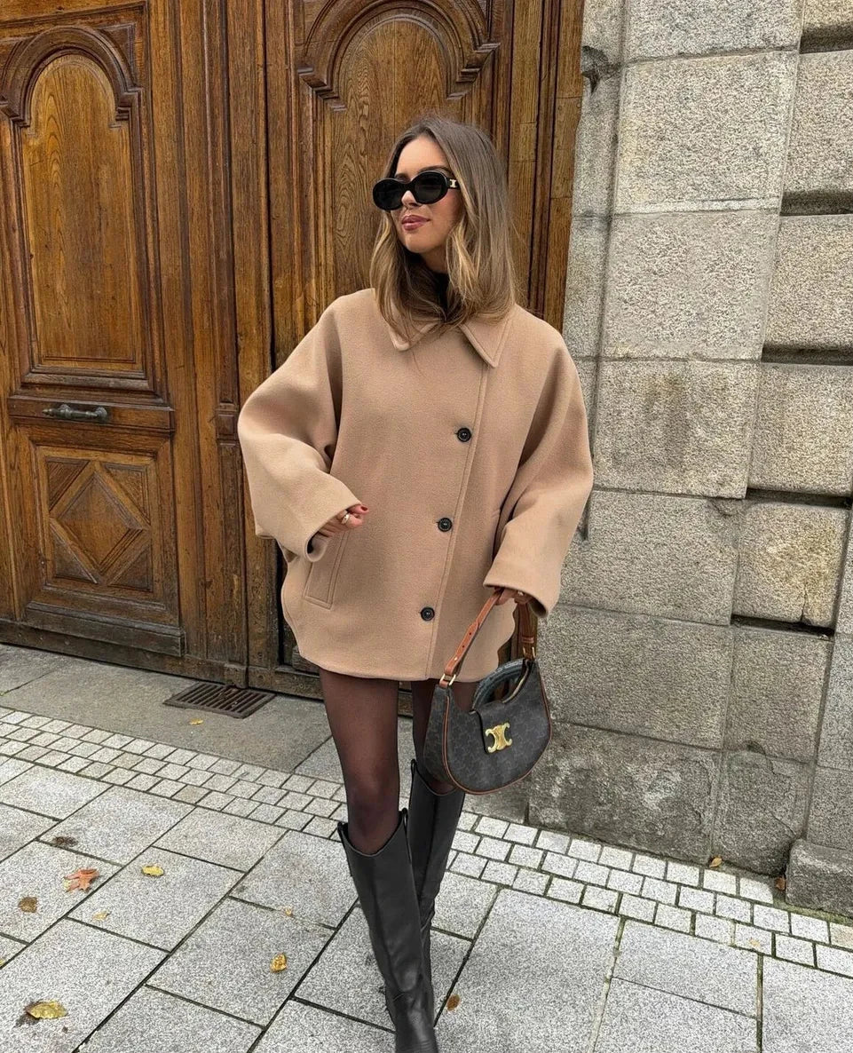 Beige oversized coat, front view against wooden doors