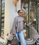 Taupe short cape, side view on model leaning against scooter