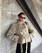Close-up of beige short belted trench coat on model