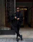 Black oversized coat with scarf and trousers, front view by doorway