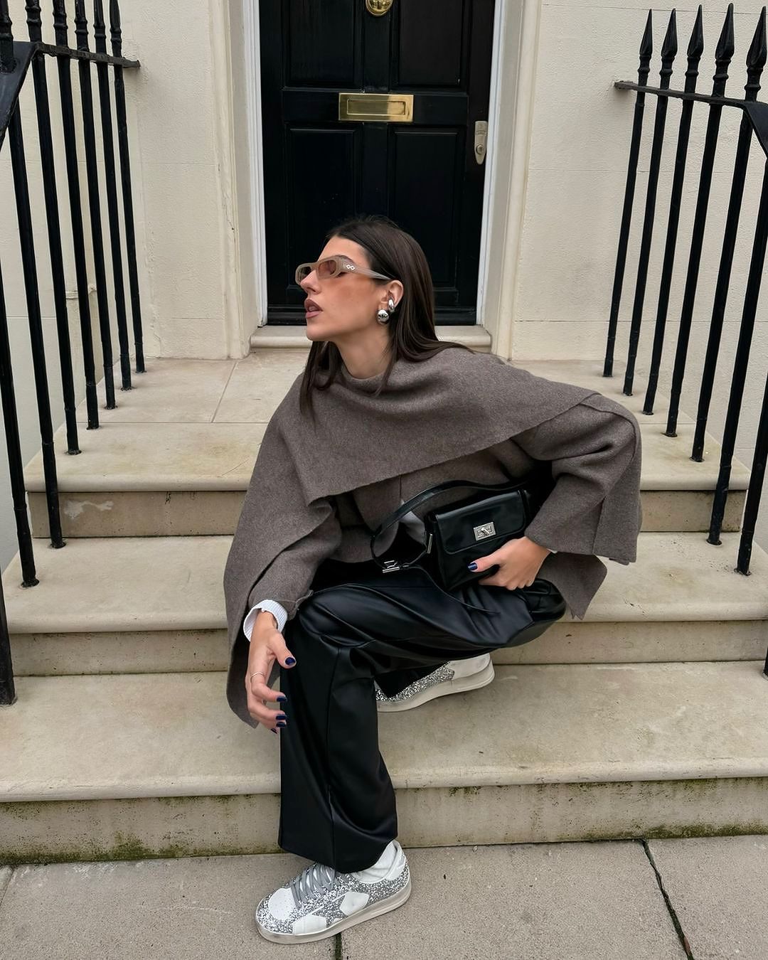 Taupe short cape, model crouched on steps, front view