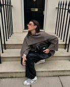 Taupe short cape, model crouched on steps, front view