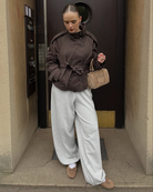 Brown short trench coat with belted waist, model in doorway
