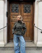 Olive green short belted trench coat, front view on model