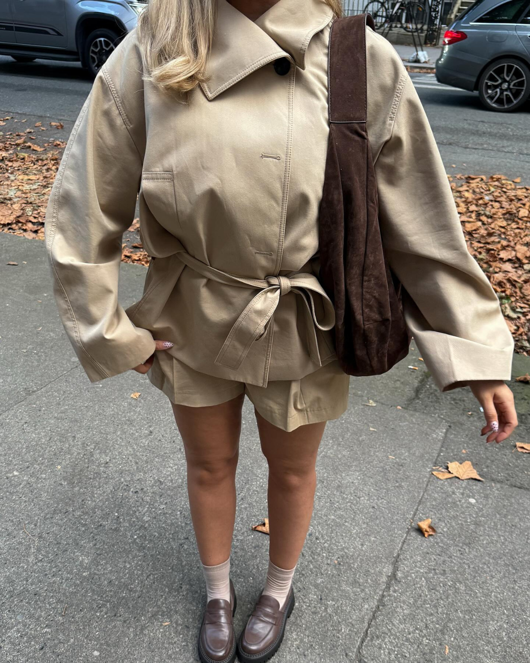 Close-up of beige belted trench jacket and shorts on model