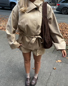 Close-up of beige belted trench jacket and shorts on model