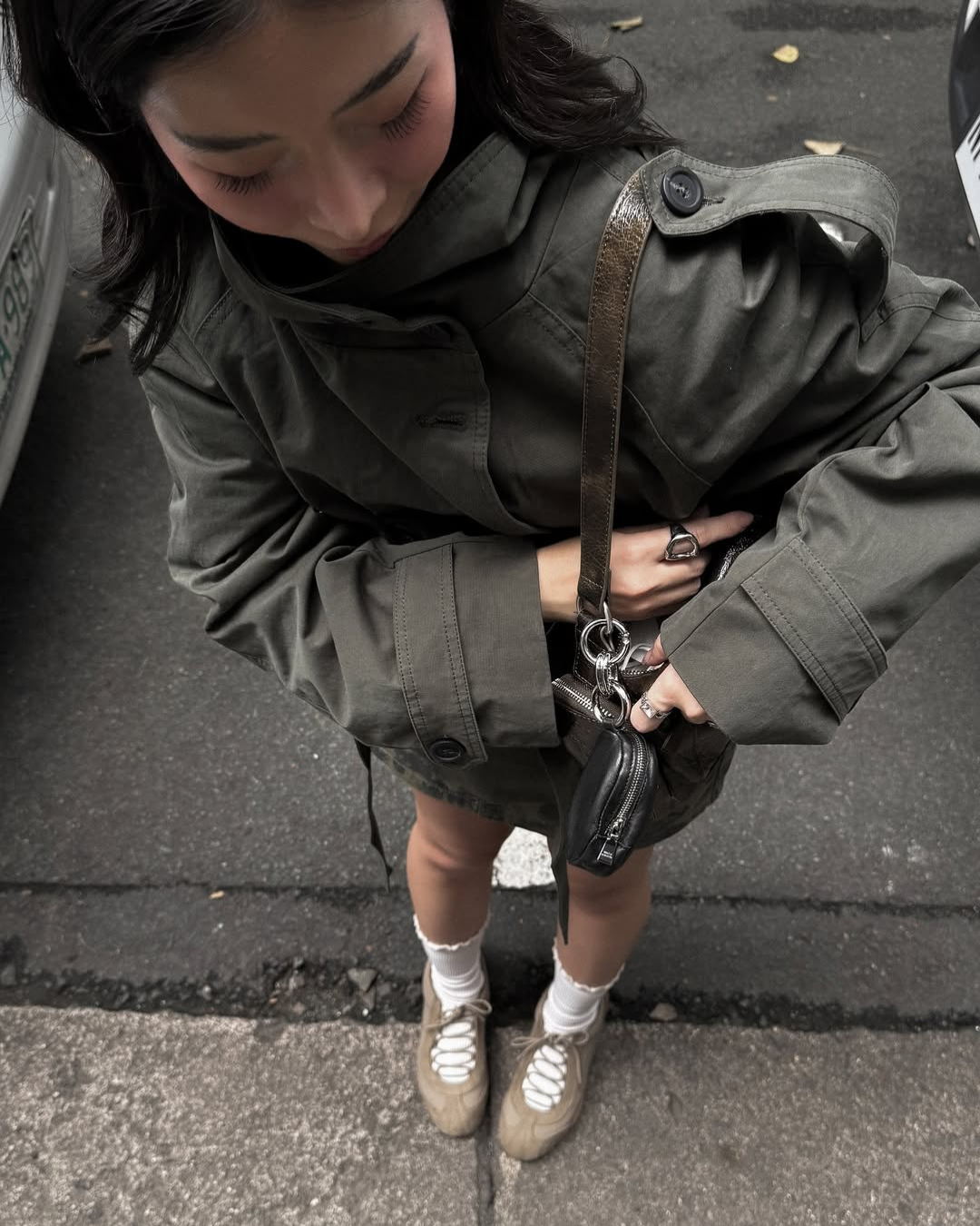 Olive green short belted trench coat, overhead close-up on model