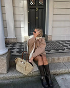 Beige oversized coat, side view seated on steps