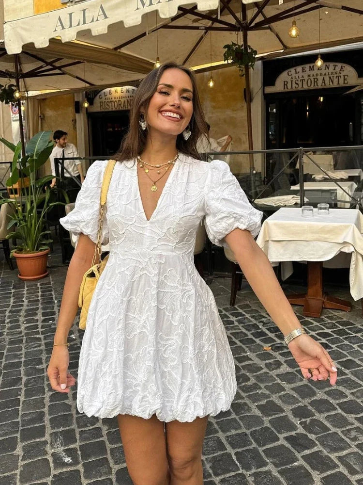 White embroidered mini dress with scalloped hem, front view on model