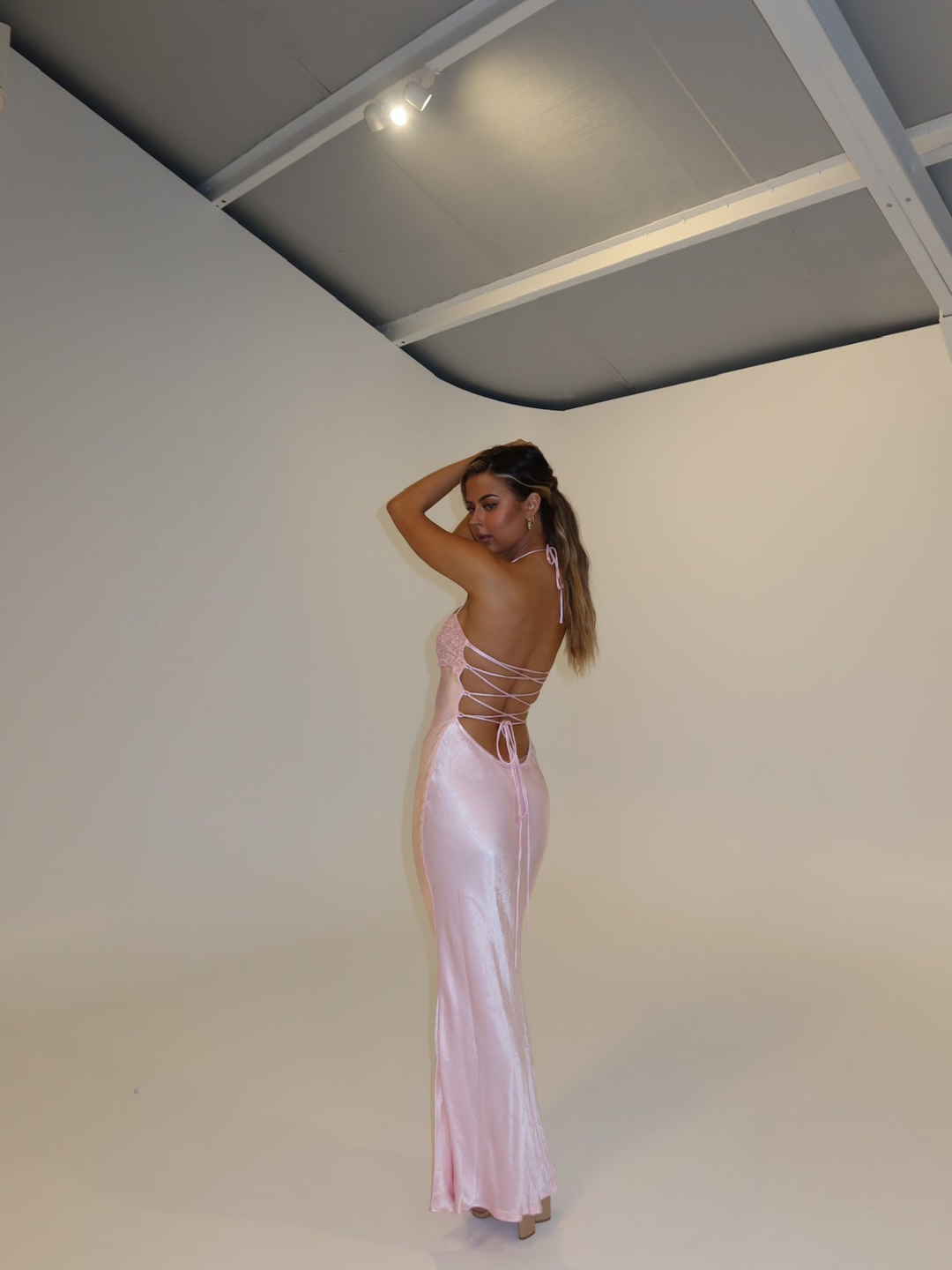 Pink satin slip maxi dress with lace-up open back, back view on model