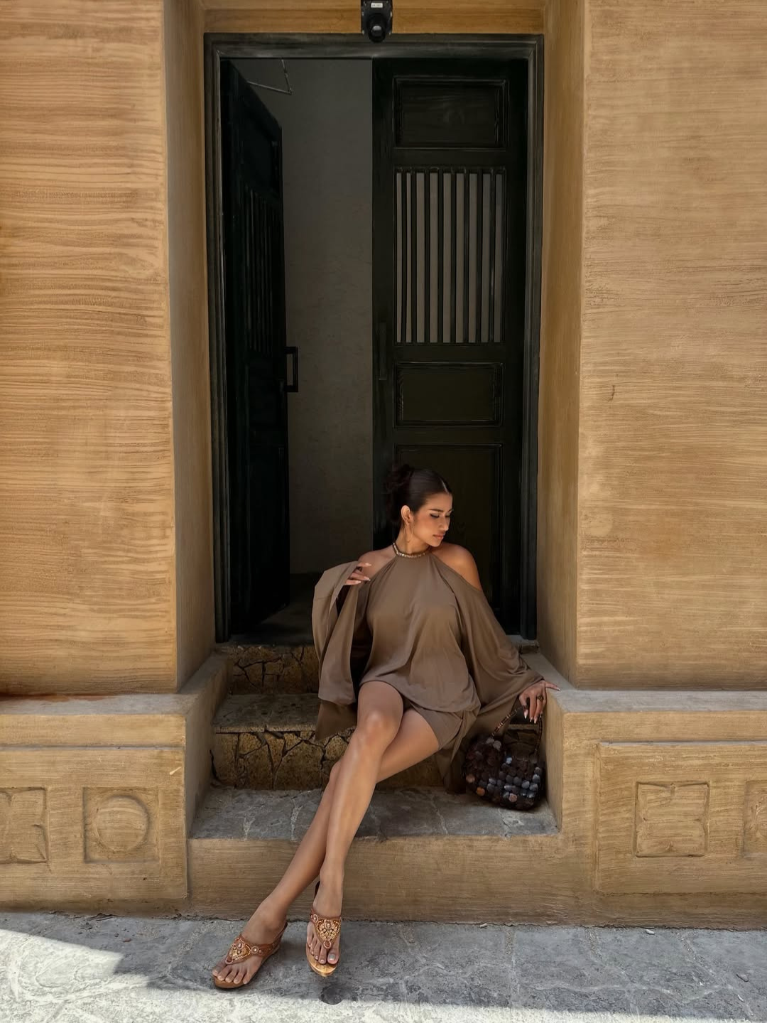Taupe halter mini dress, model seated on steps, front view