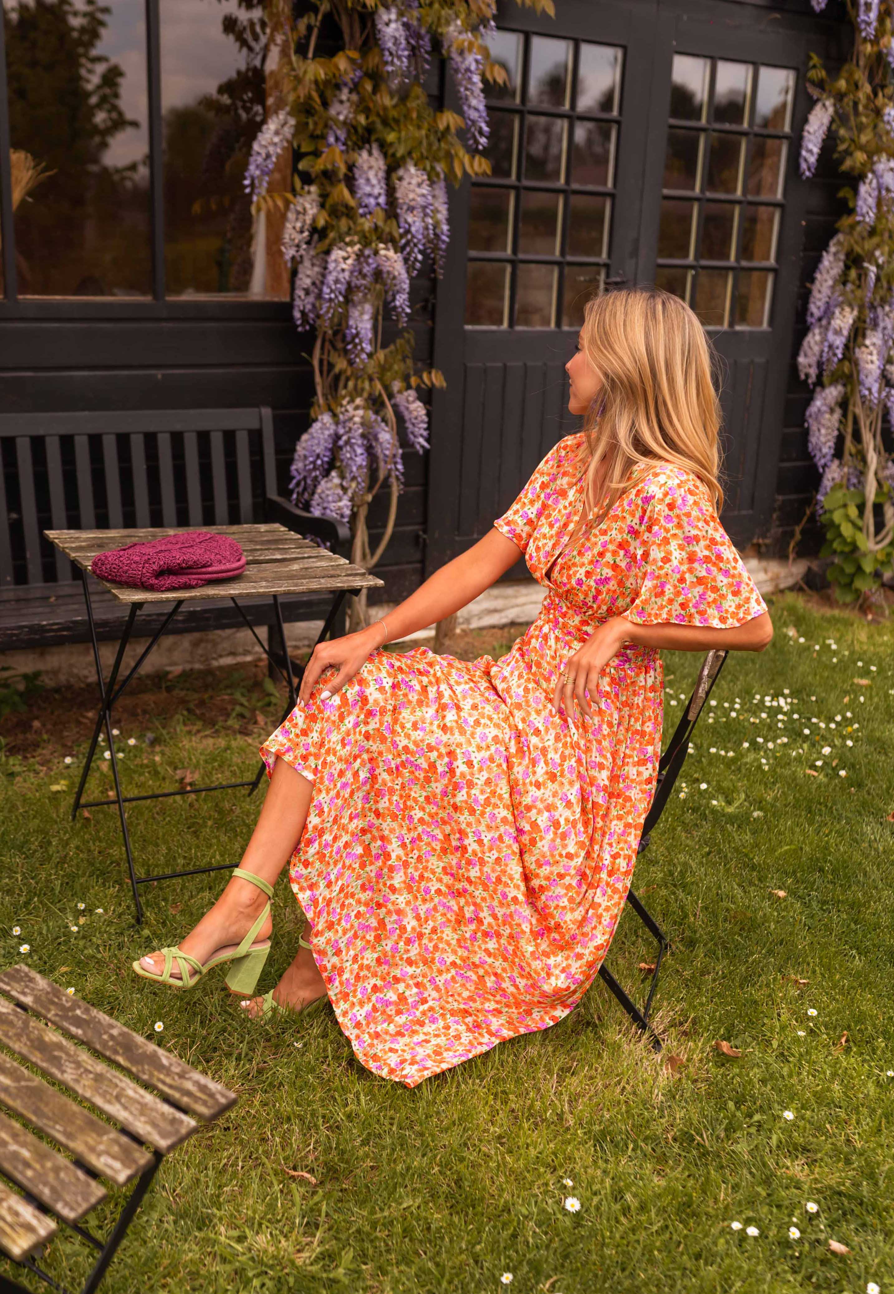 Orange floral print maxi dress, seated side view on model