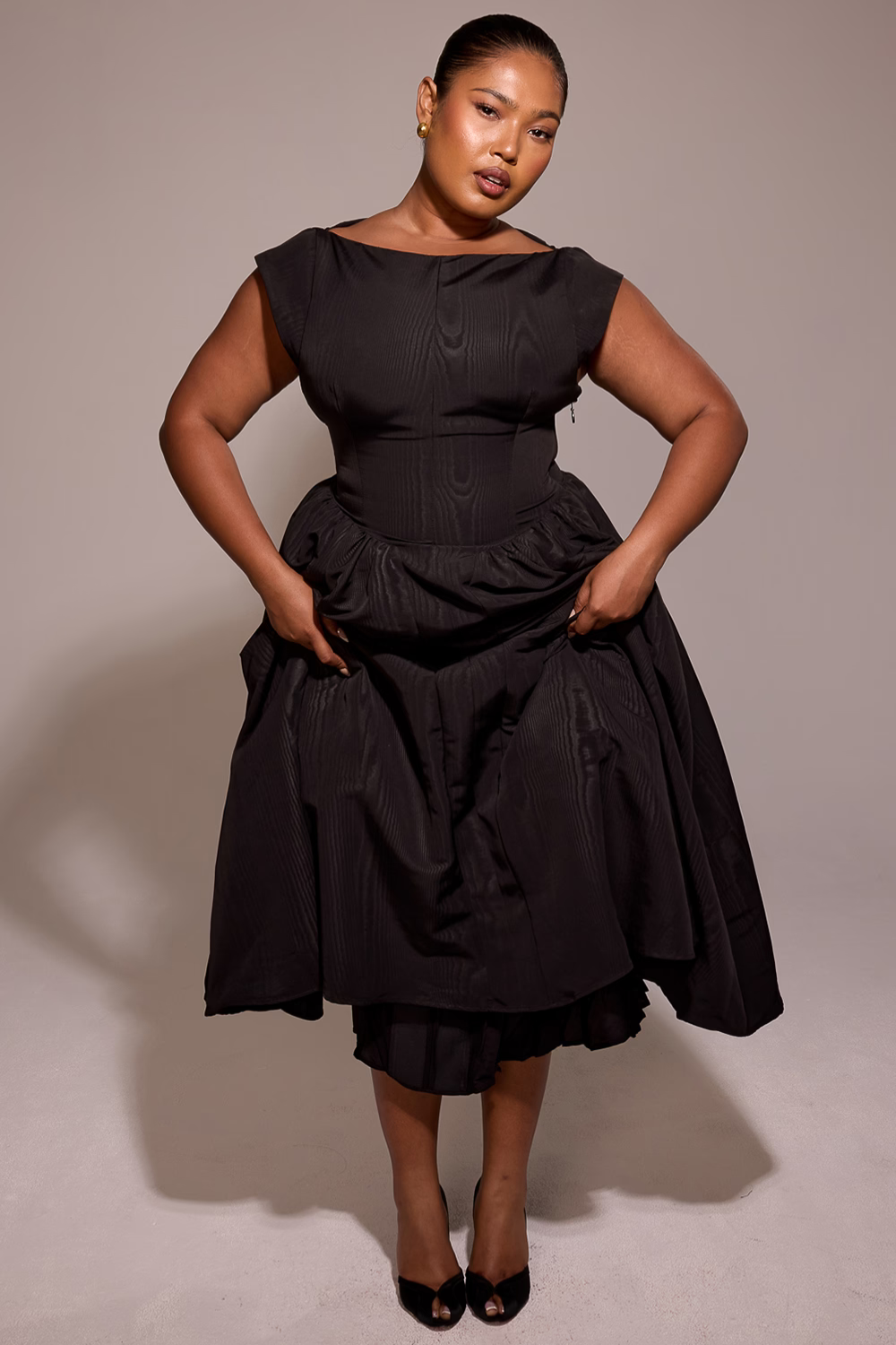 Black full-skirt midi dress, model gathering the skirt