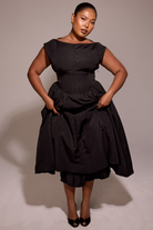 Black full-skirt midi dress, model gathering the skirt
