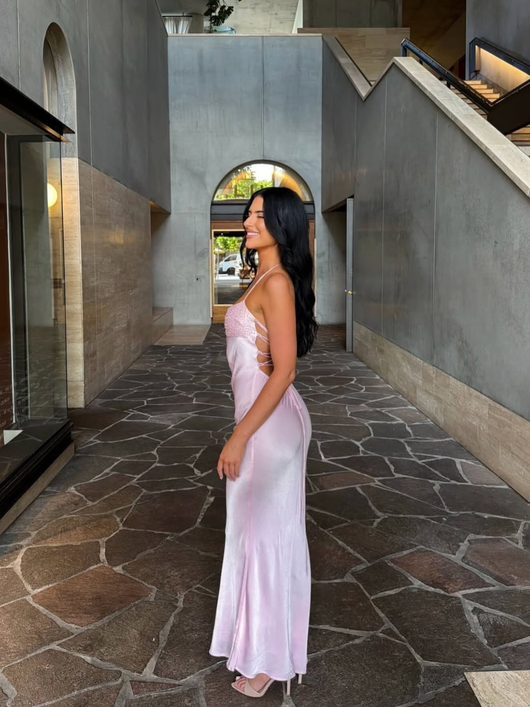 Pink satin slip maxi dress, side view on model in courtyard