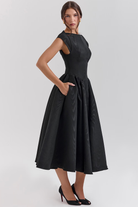 Black full-skirt midi dress, side view with hand in pocket