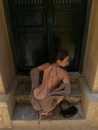 Taupe mini dress with beaded back straps, model crouching, back view