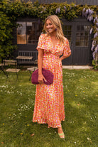 Orange floral print maxi dress, smiling front view on model outdoors