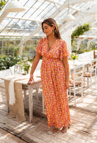 Orange floral print maxi dress, front view on model indoors