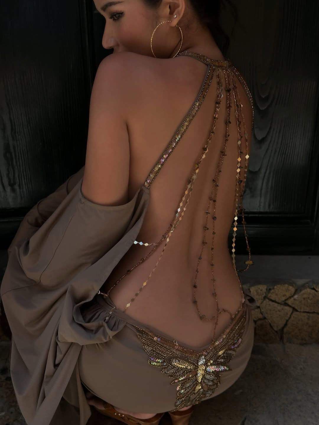Close-up of beaded shoulder chain and butterfly detail on taupe mini dress