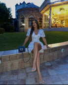 White and blue floral mini dress, model seated, crossed legs, evening light