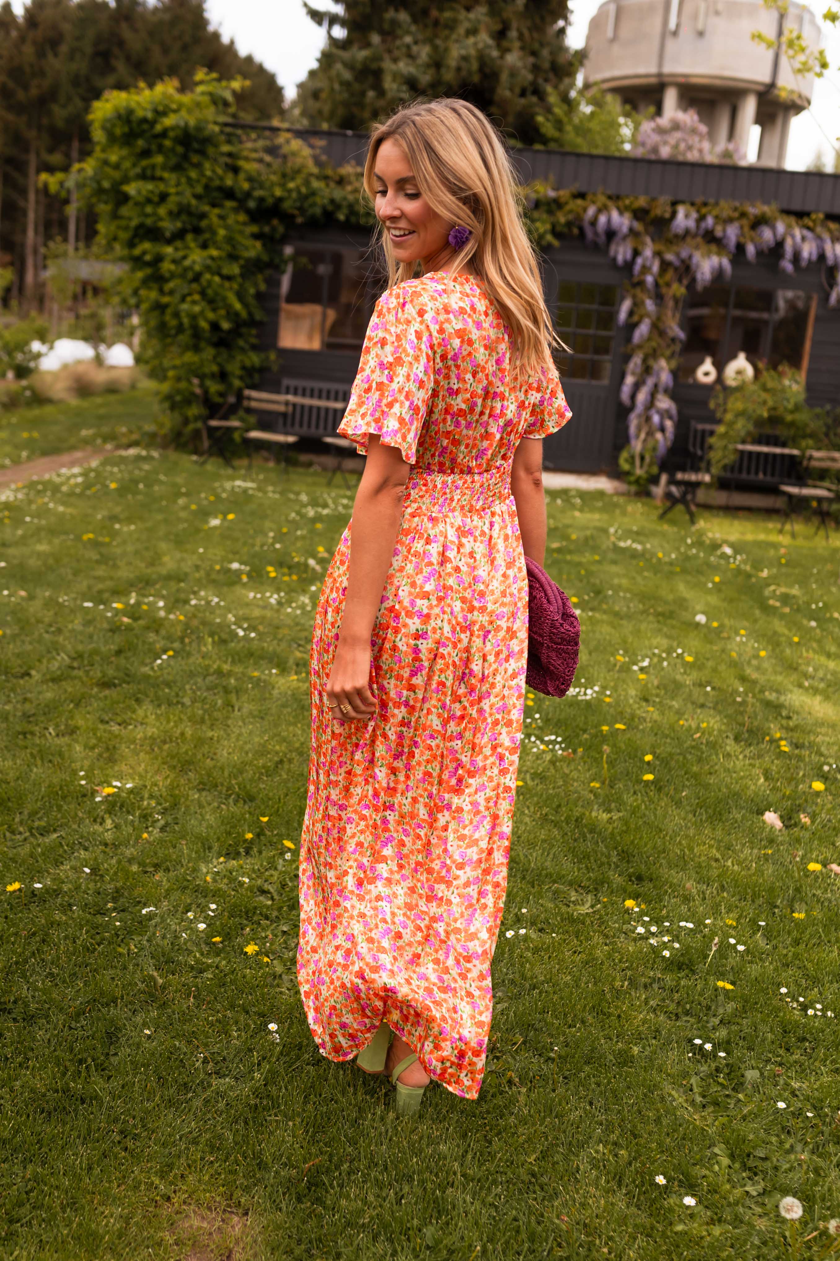 Orange floral print maxi dress, back view with model looking over shoulder