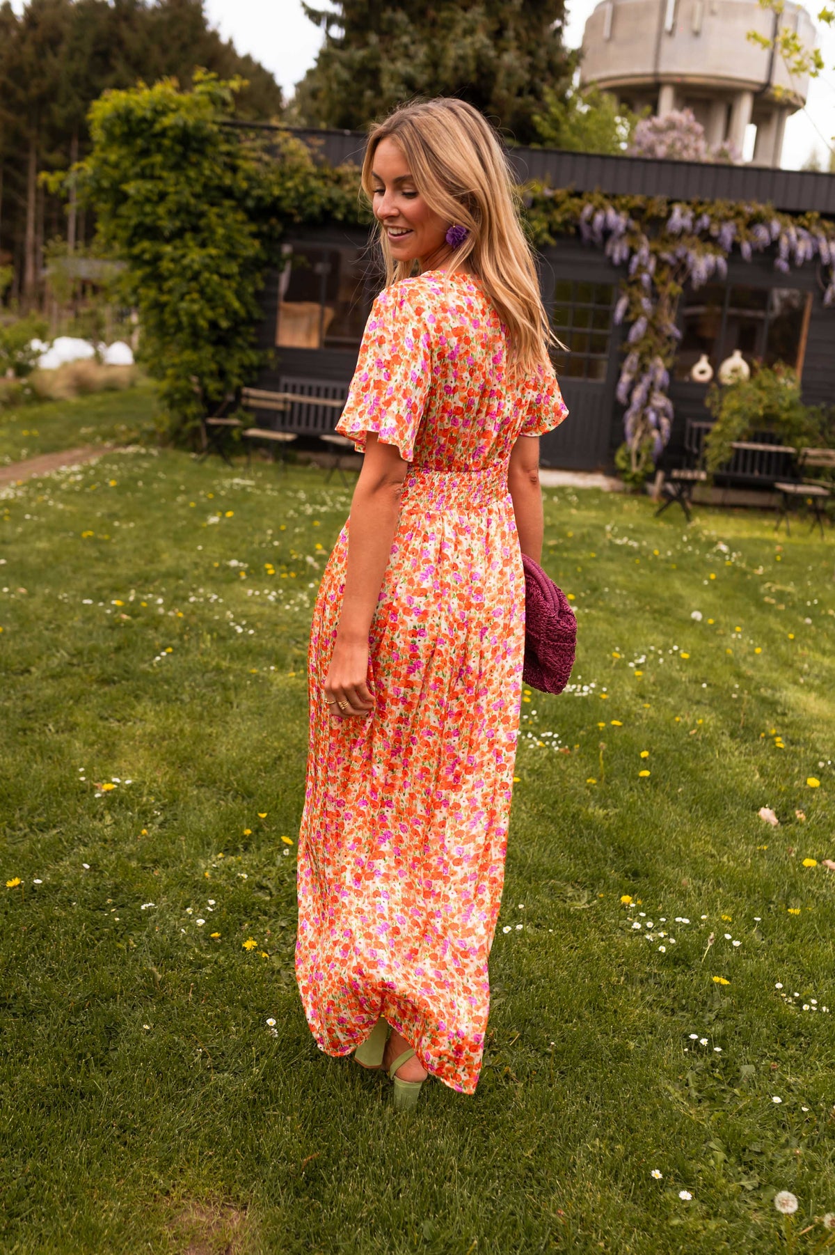 Orange floral print maxi dress, back view with model looking over shoulder