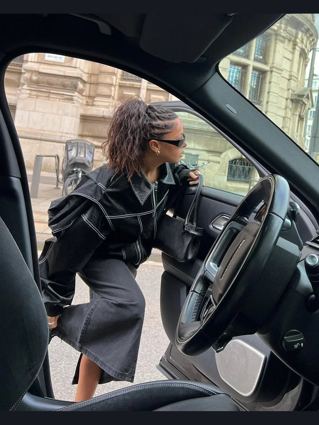 Black oversized contrast-stitch jacket over denim skirt, side view getting into car